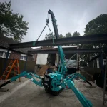 Spider crane lifting steel beams in tight backyard space
