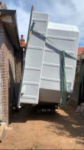 Tracked carrier transporting a fiberglass pool through a tight-access residential jobsite