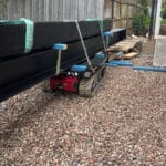 Tracked carrier transporting steel beams on uneven ground