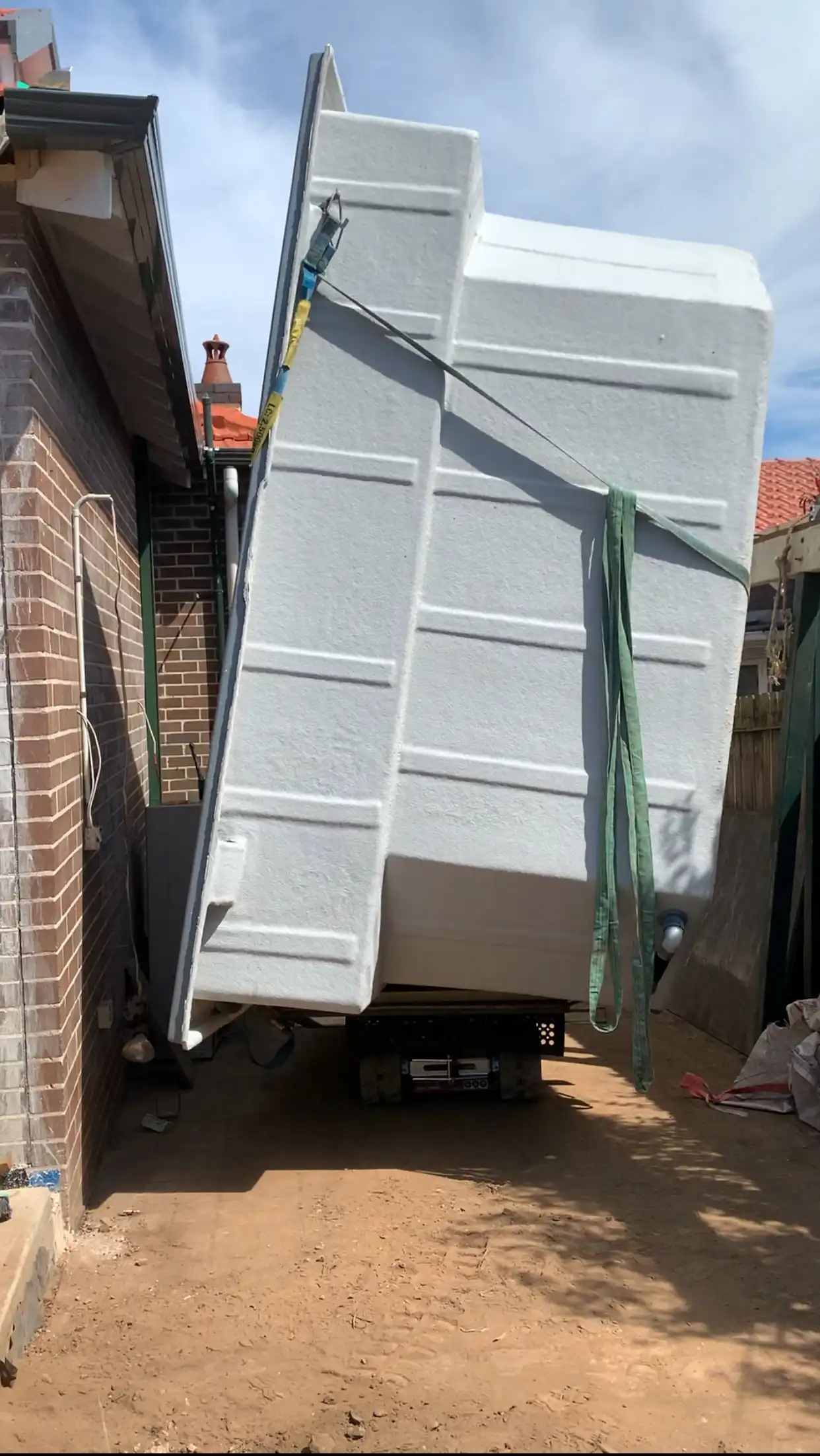 Tracked carrier transporting pool down the side of a house