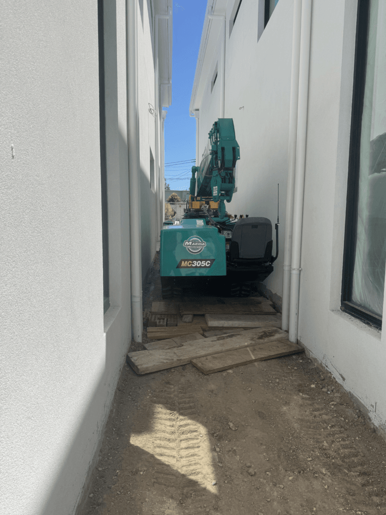 Maeda 305 mini crane squeezing through a narrow Sydney laneway to reach a tight-access site