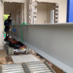 tracked carrier transporting 12m steel beam through house in tight access construction site