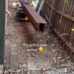 tracked carrier transporting steel beams through narrow side access of residential site