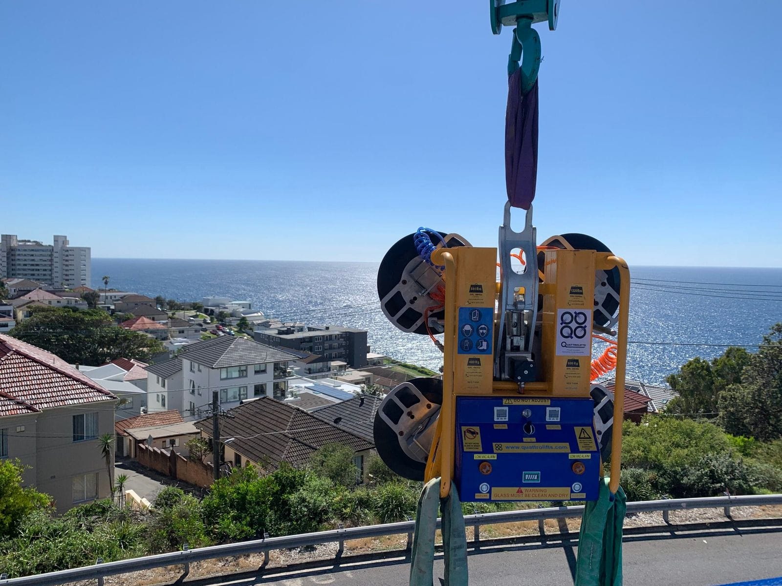 Crane hire Central Coast — vacuum lifter craning a glass panel above the coastline