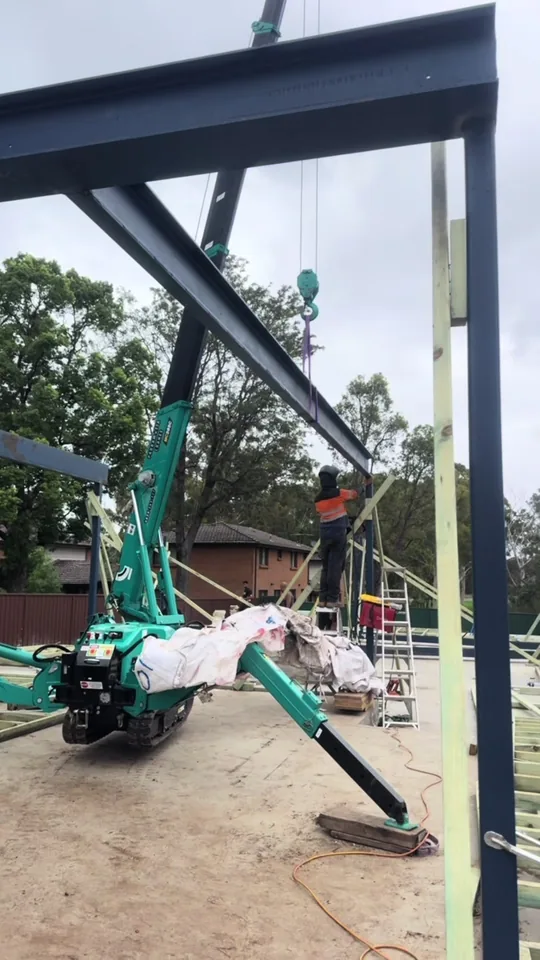 Maeda spider crane flying a steel beam into a tight access backyard frame in Sydney